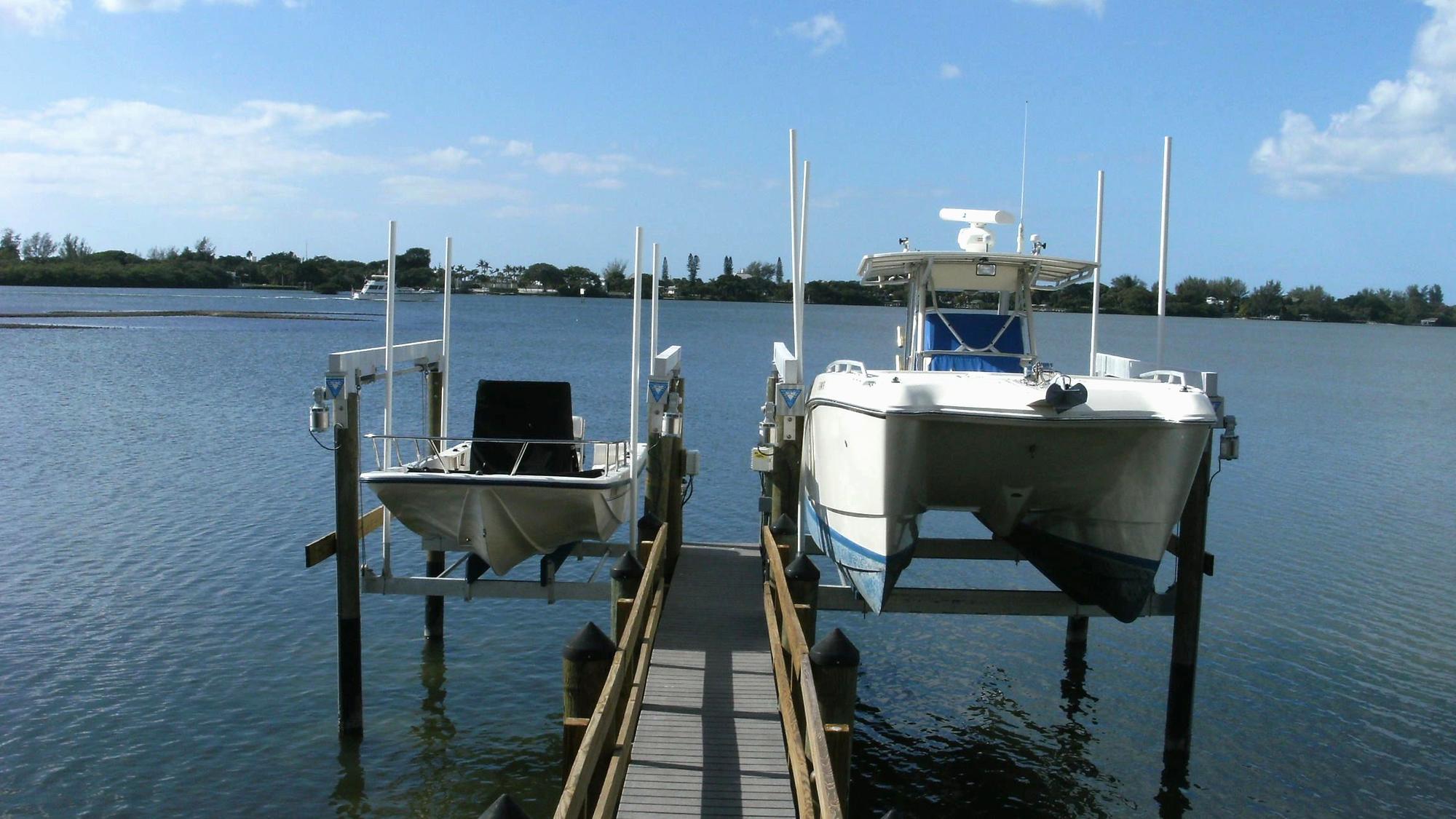 Two boats on Ram Marine lifts beside a private dock on Sarasota Bay