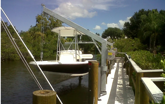 Davit lifting a center console boat beside a dock