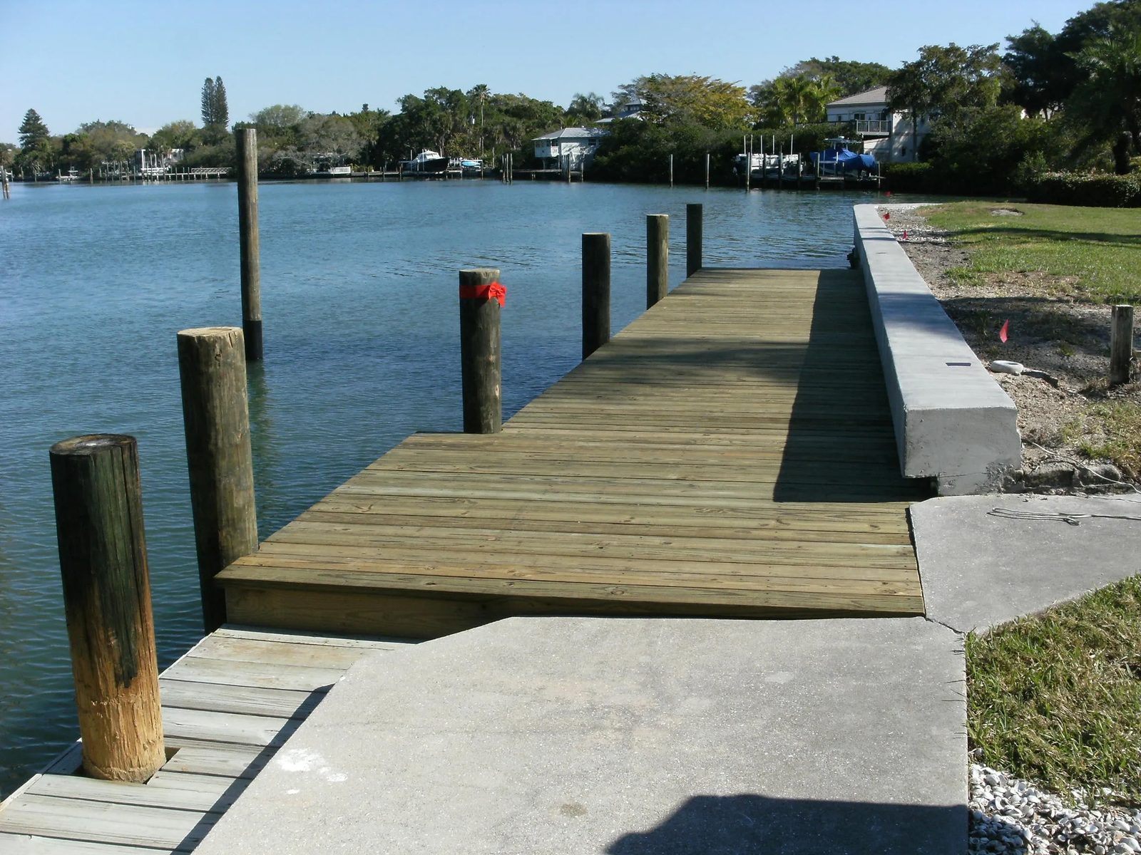 Timber dock stepping down alongside a newly built concrete seawall on a Sarasota County canal